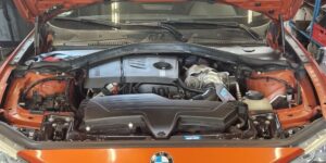 BMW 116i F20 N13B16 - Fahrzeug von vorne mit geöffneter Motorhaube bei Motorschmiede